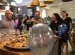 Many members celebrating a 2 year anniversary in NGIN Workplace's kitchen and dining area, with food, wine, and balloons.