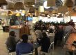 Many NGIN Workplace team members sitting and watching a member show and tell