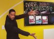 Will Smith cardboard cutout placed in front of an NGIN Workplace Boston Coworking Space Bulletin Board advertising NGIN's Got Talent
